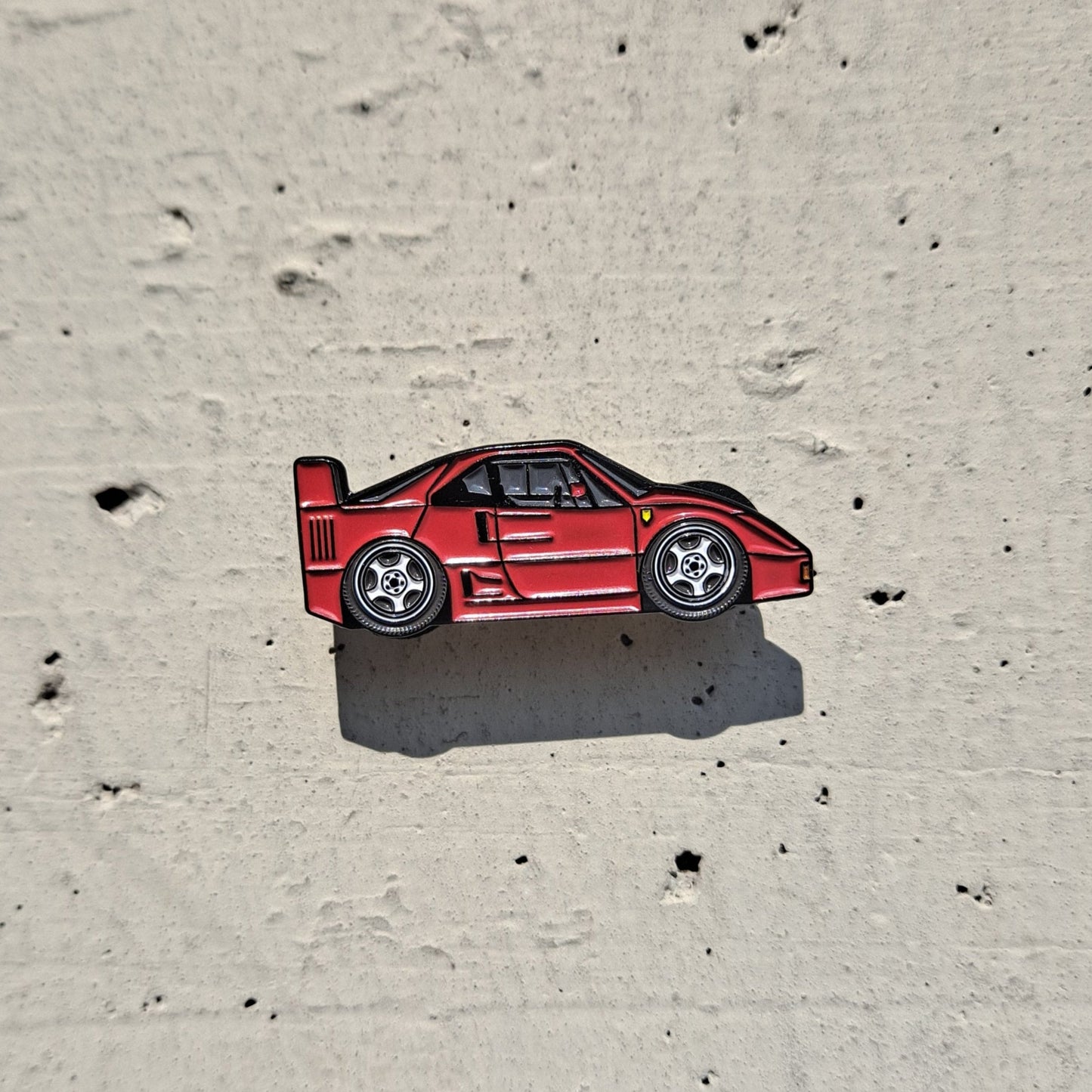 Ferrari F40 red enamel pin on cement background