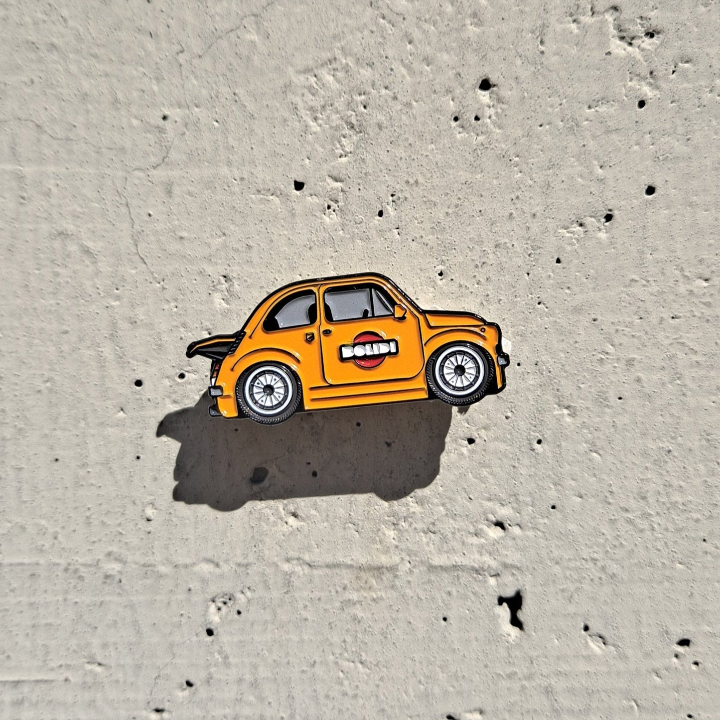 Fiat 500 1971 yellow enamel pin on cement background