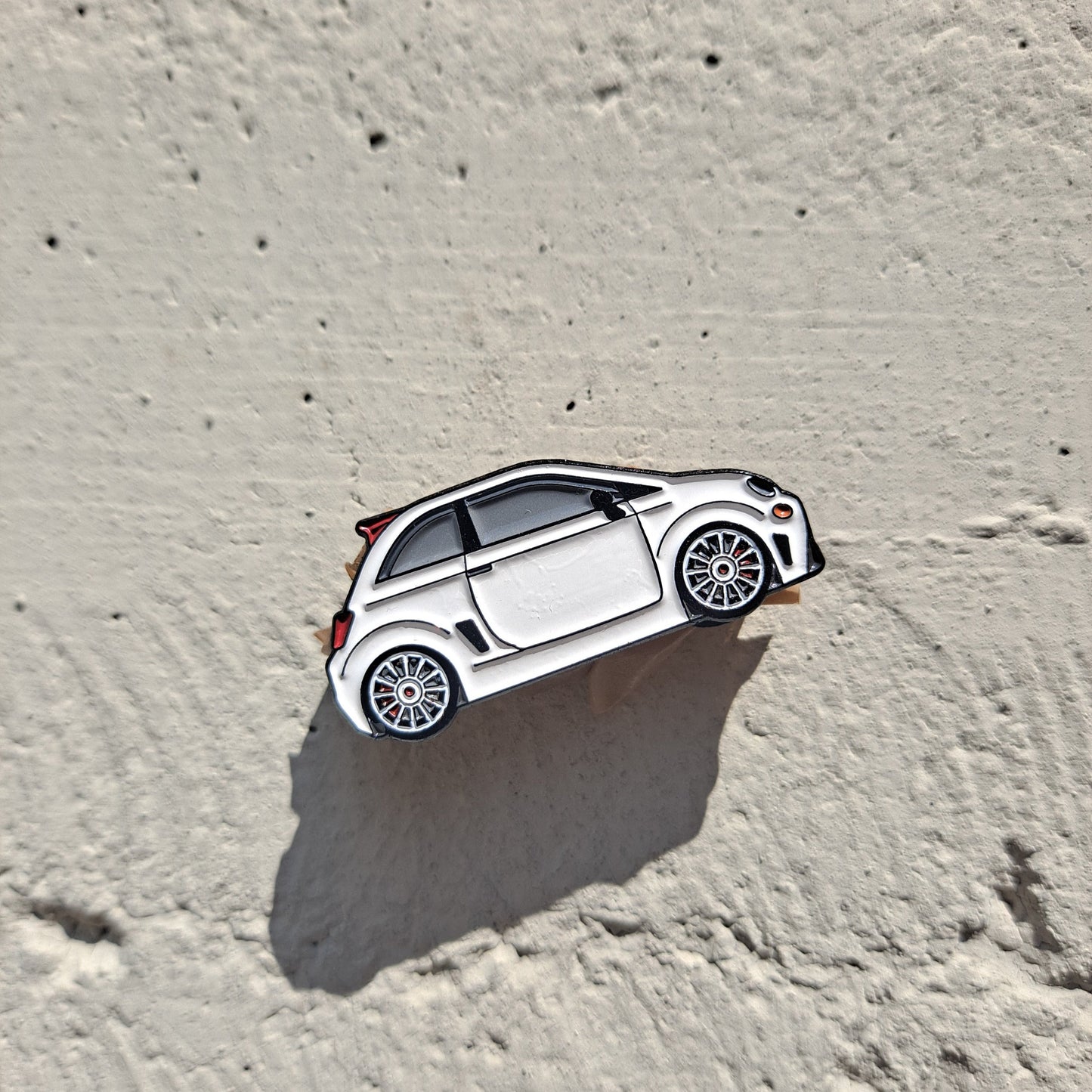 Fiat 500 Abarth enamel pin on cement background