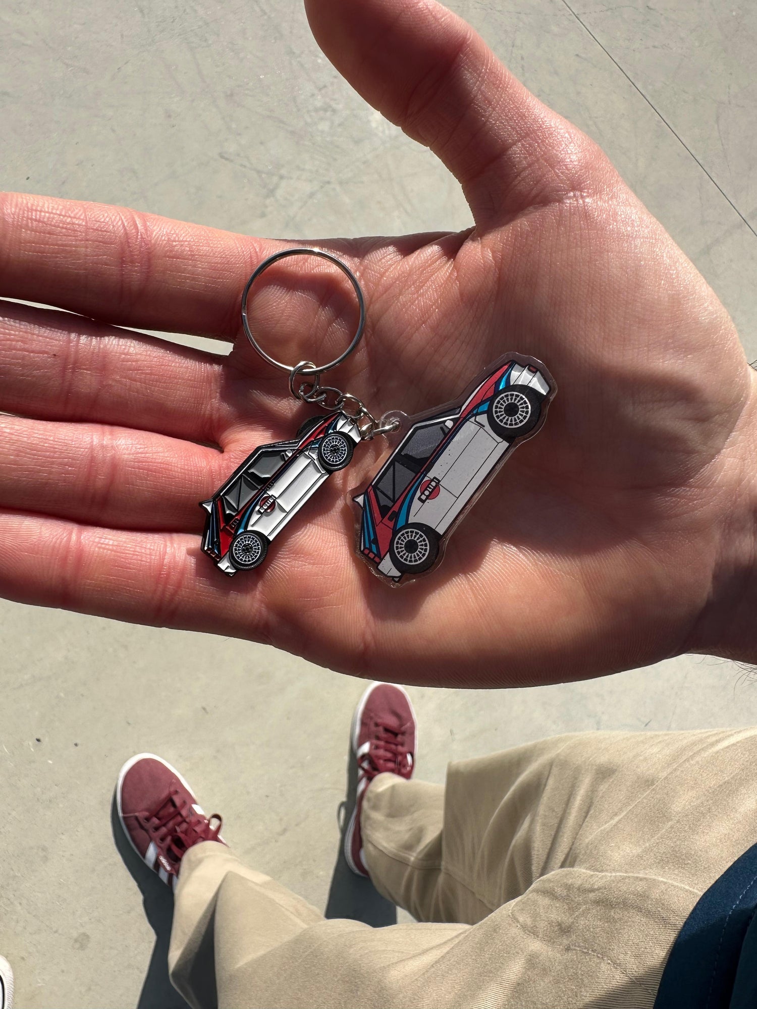 Lancia Delta pin and keychain shown on a hand