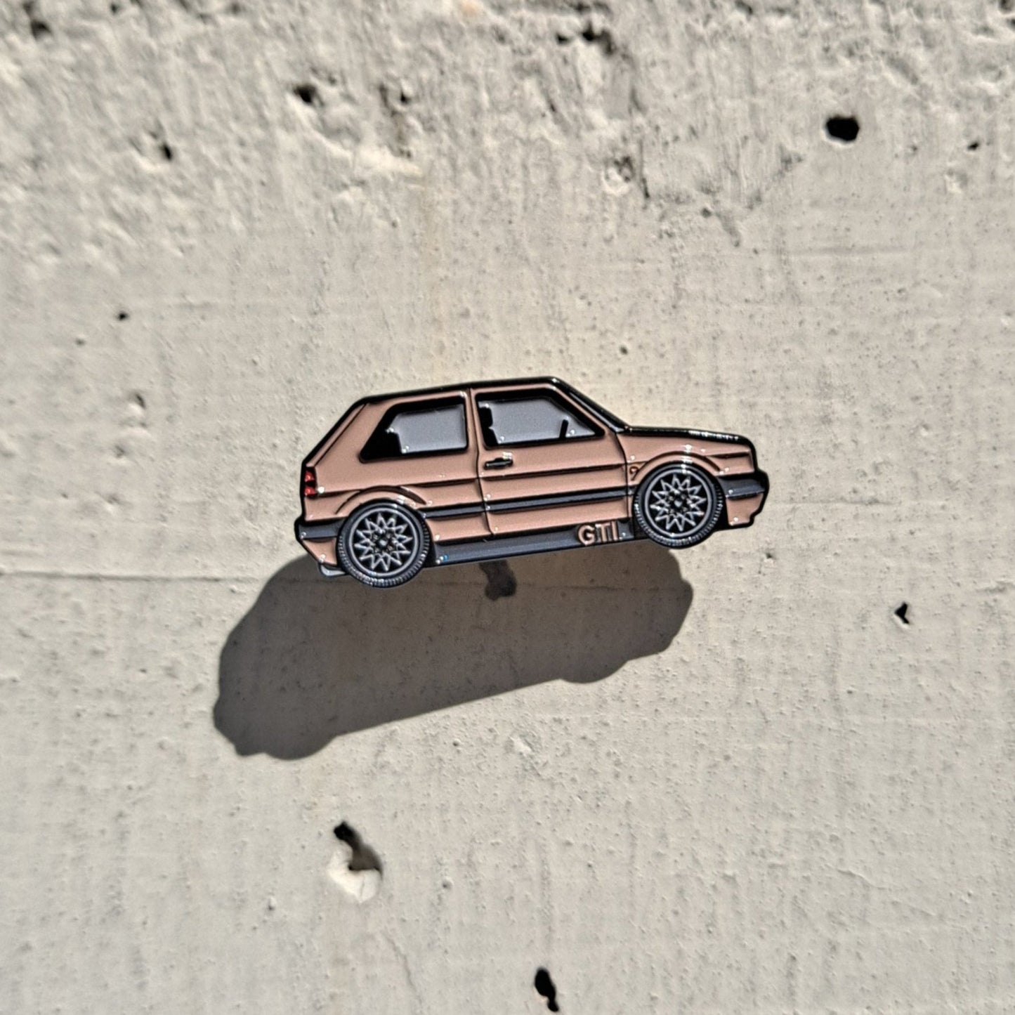 Volkswagen Golf MK2 brown enamel pin on cement background