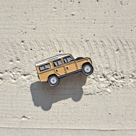 Defender Series III Sand Enamel Pin featuring the iconic Land Rover Defender design in sand color, with high-quality enamel finish and double black rubber pin clutches on the back